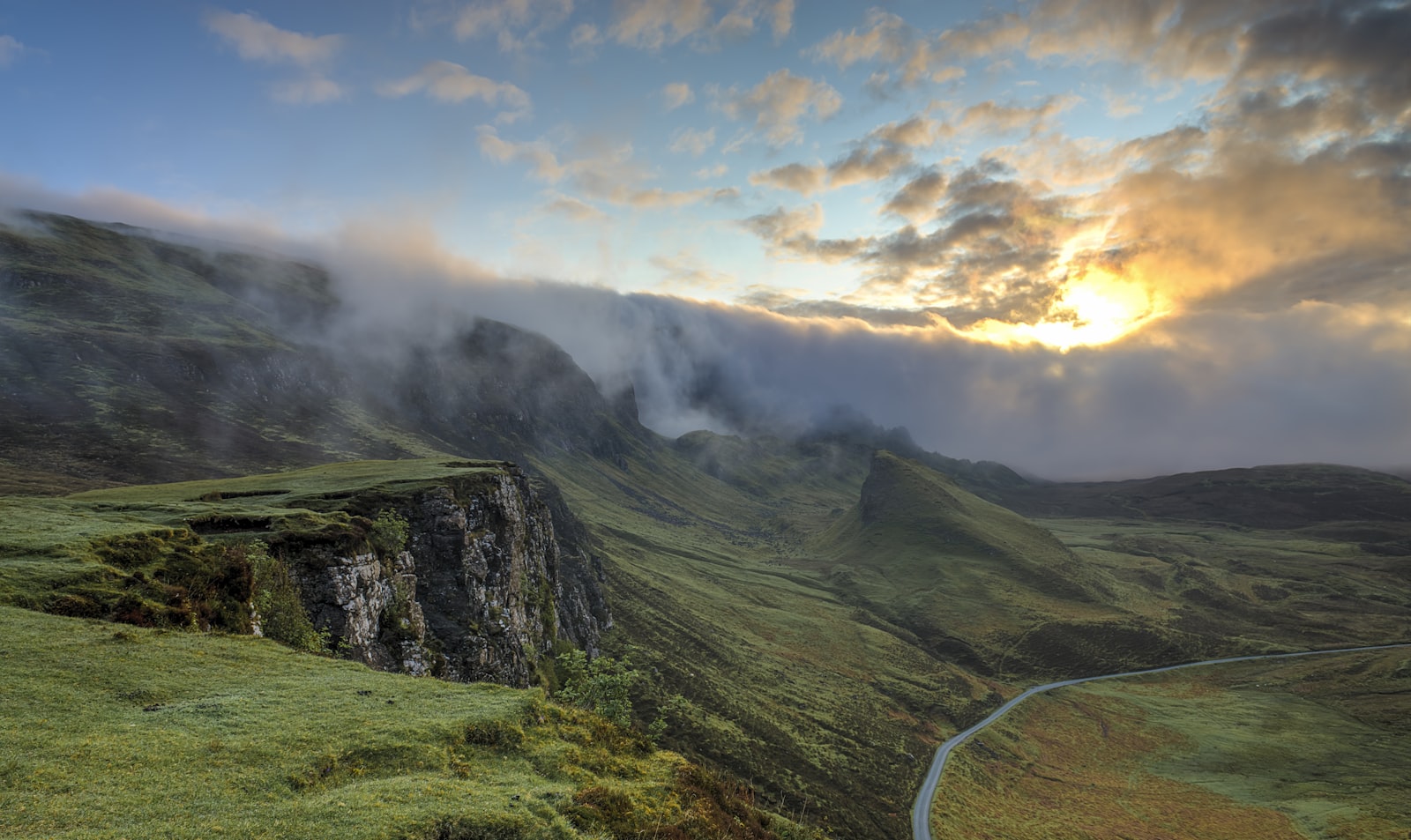 Sunrise over green highland cliffs with drifting clouds